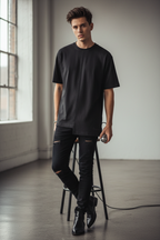 Slim male singer wearing black high/low t-shirt with black-on-black logo